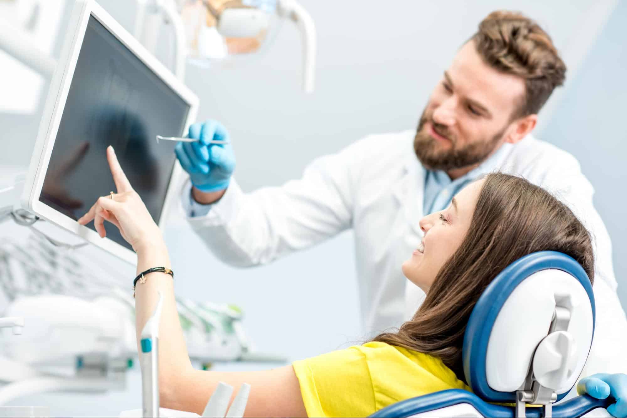 Orthodontist showing digital dental X-rays to a patient on a monitor